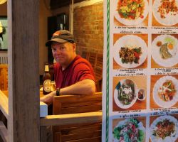 Rick at one of our favorite restaurants. Notice the large menu hanging outside. Many restaurants have similar displays. Luang Prabang, Laos.