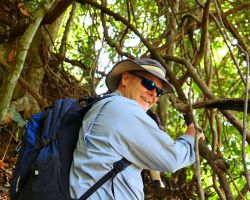 Rick jungle climbing up the tree roots on our Bolaven Plateau and waterfall trek. Pakse, Laos.