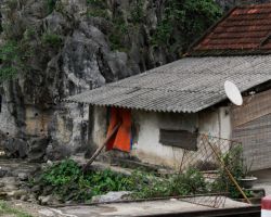 Local house/shack built directly against a huge karst. Tam Coc, Vietnam.