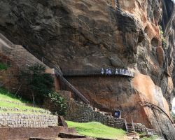 Sideview of a small portion of the 590 ft tall "Lion Rock". Note the size of the school kids walking on the platform. Sigiriya, Sri Lanka.